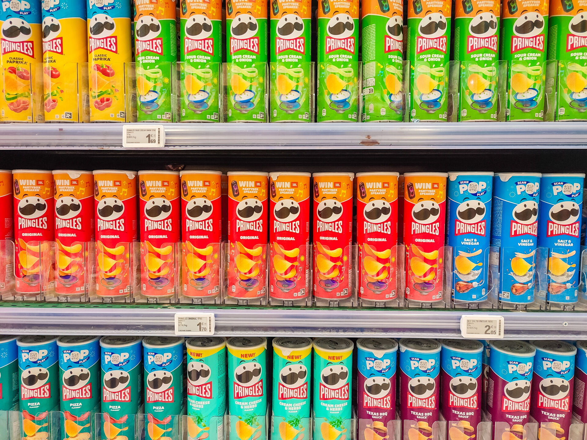 Colorful Pringles snack cans are displayed neatly on a supermarket shelf